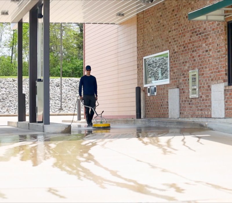 professional using pressure washer to pressure wash concrete at commercial property