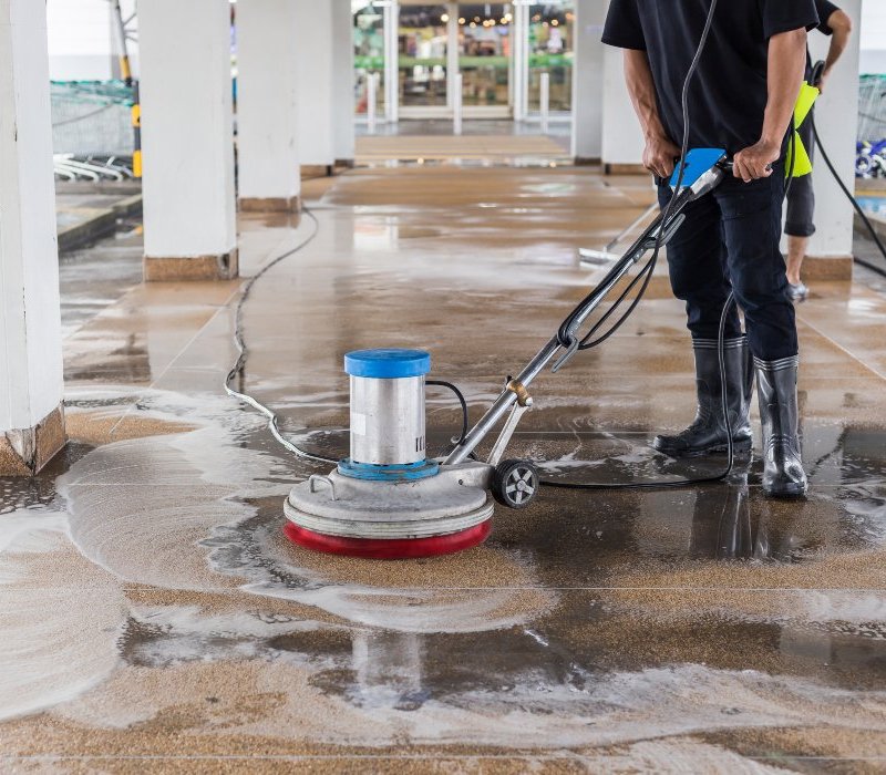 Worker using a floor scrubber for commercial pressure washing